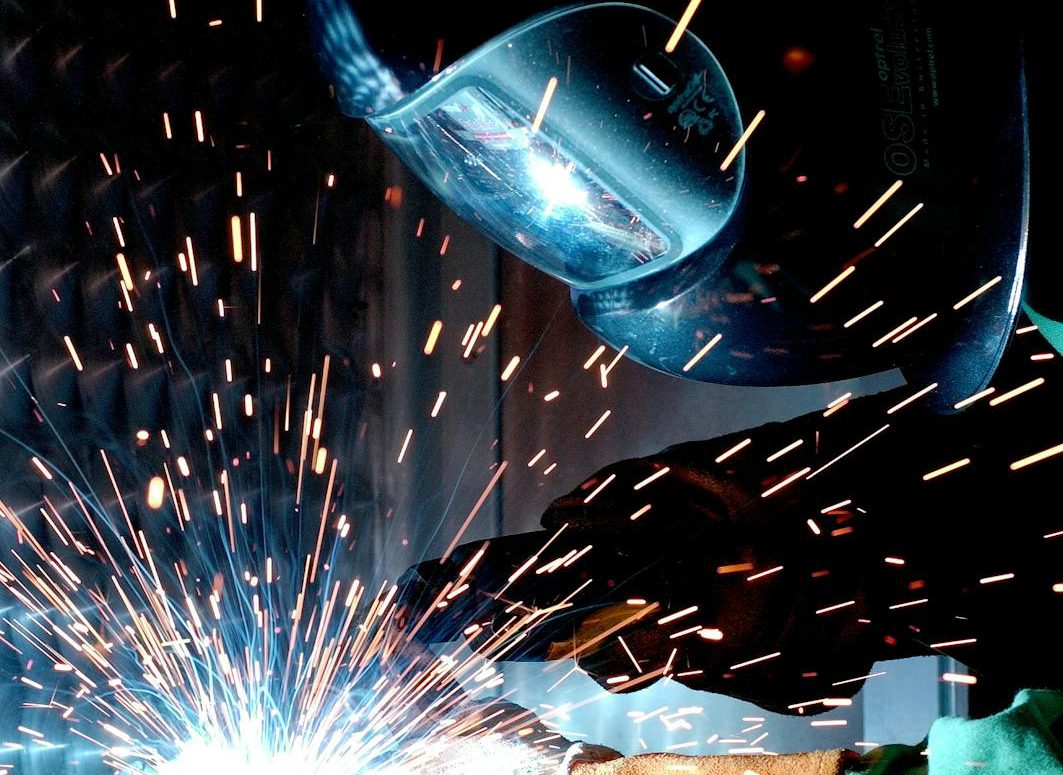 Person in Welding Mask While Welding a Metal Bar