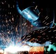 Person in Welding Mask While Welding a Metal Bar